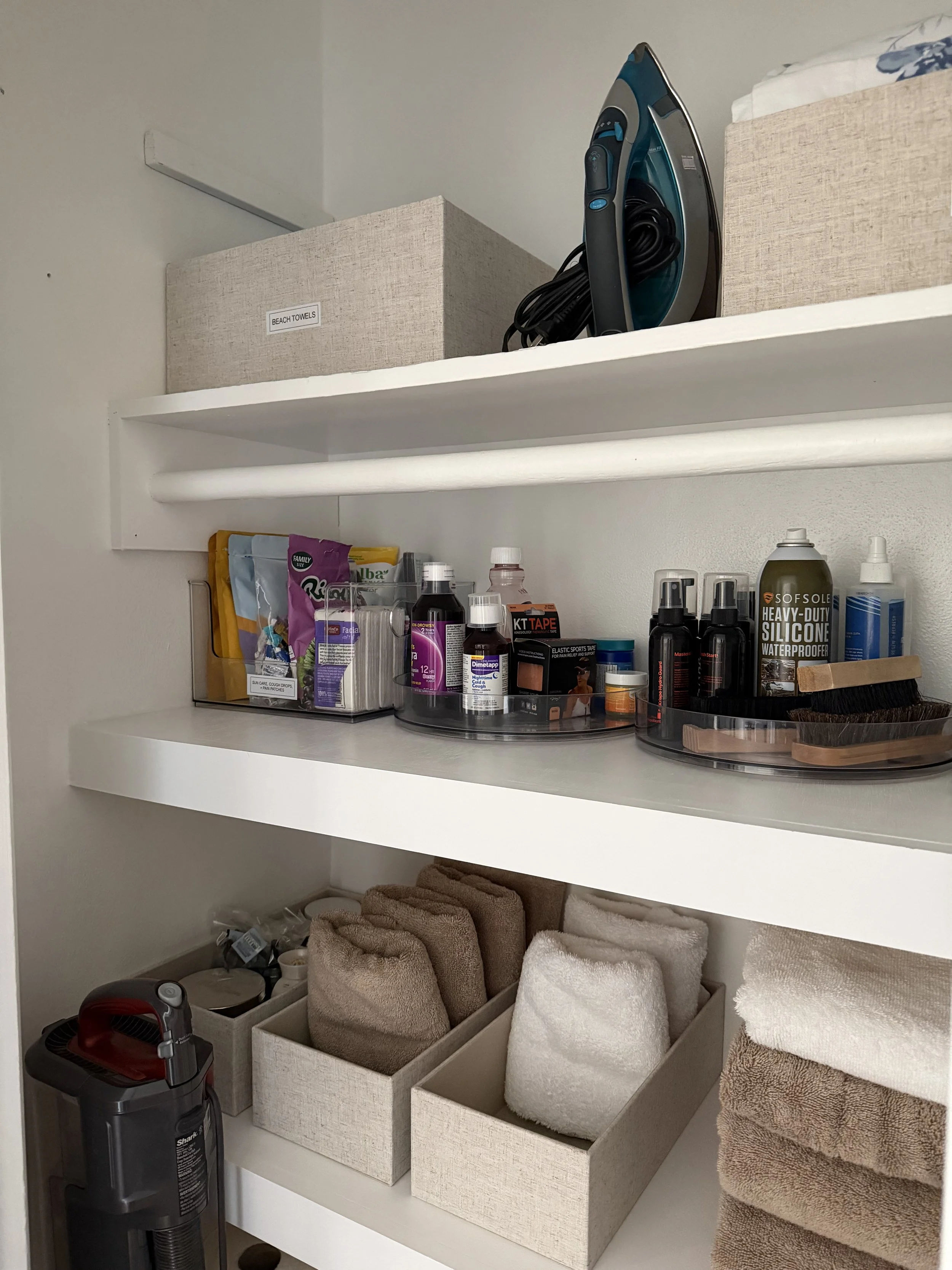 hall closet with white shelves and organizing bins