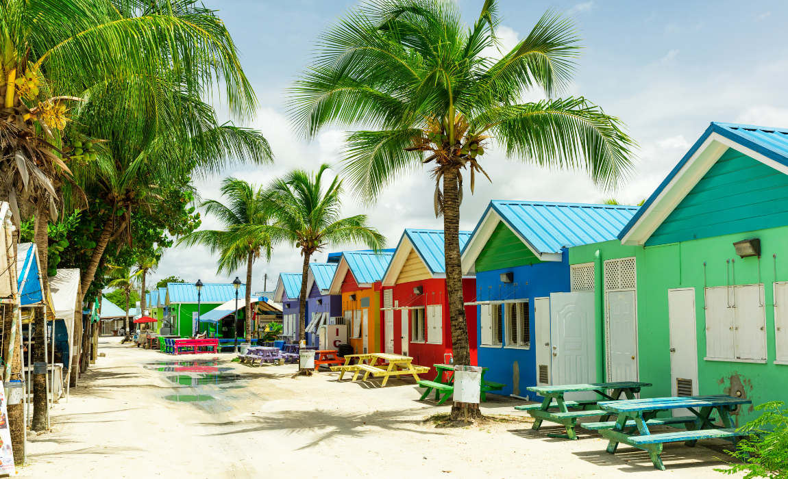 Bright colored cabanas with picnic tables and palm trees