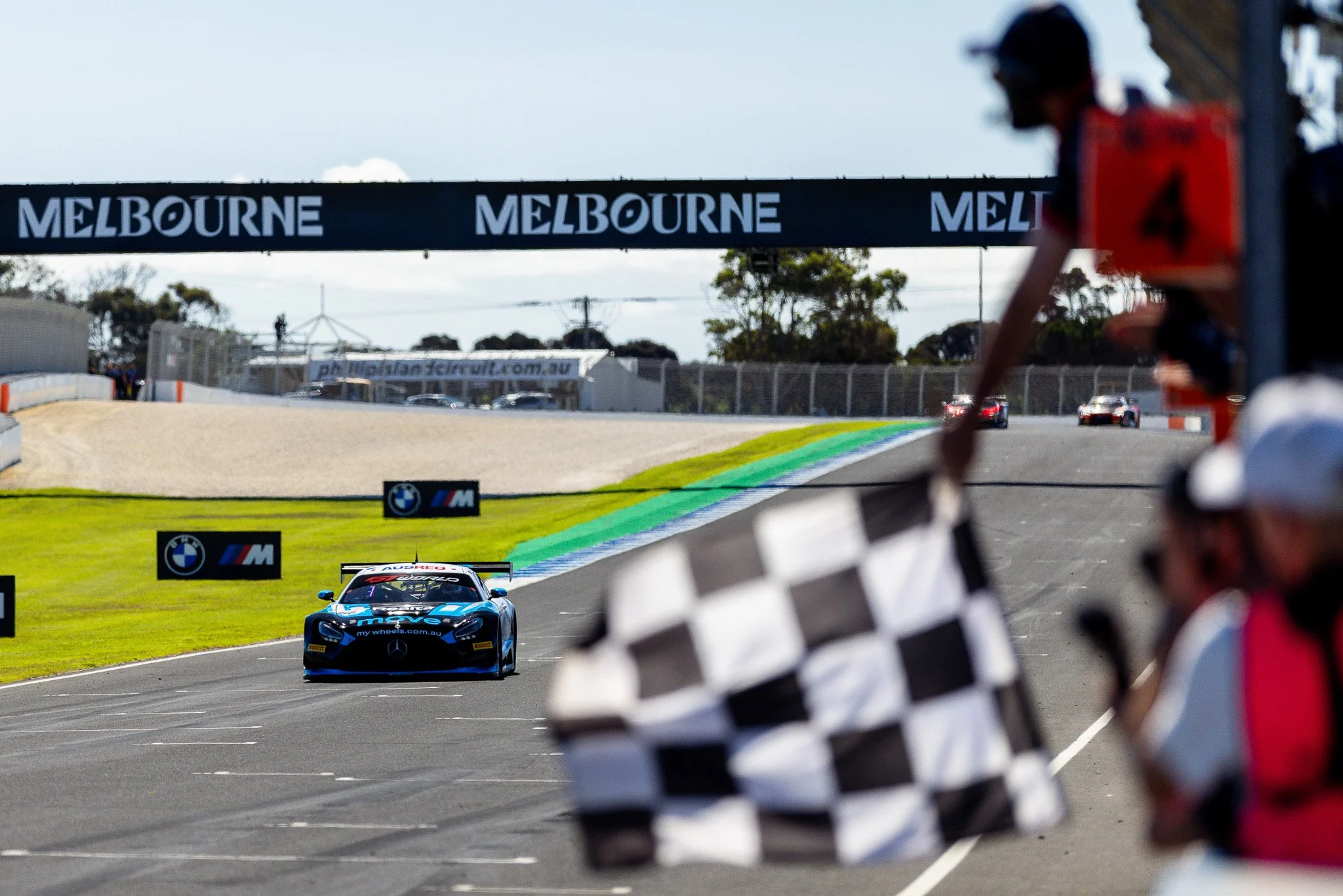 Racing car on track with Mercedes-Benz branding, colorful paint design, and logos including AXON and Bridgestone.