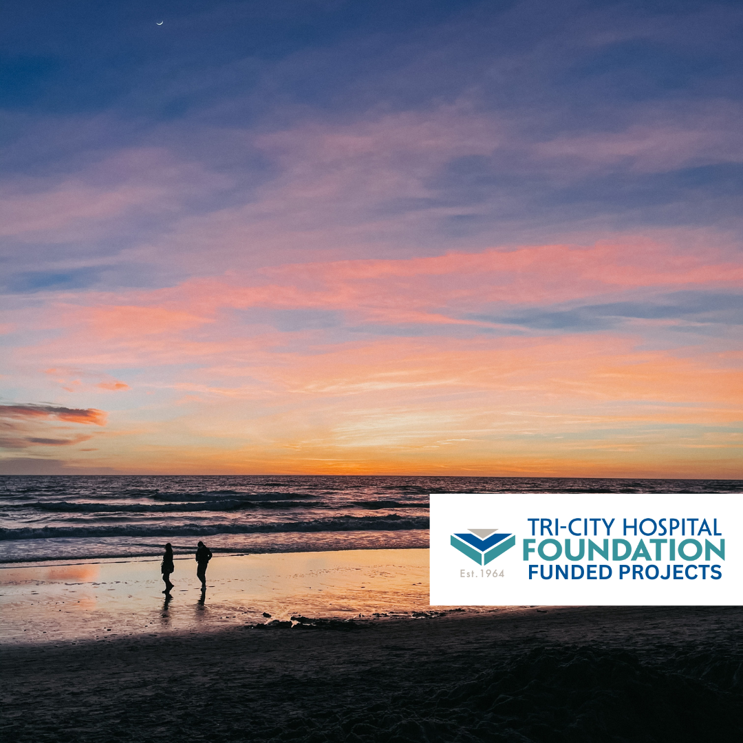 A sunset over the ocean with pink and orange clouds in the sky, two people standing on the beach, and a logo of Tri-City Hospital Foundation in the bottom right corner.