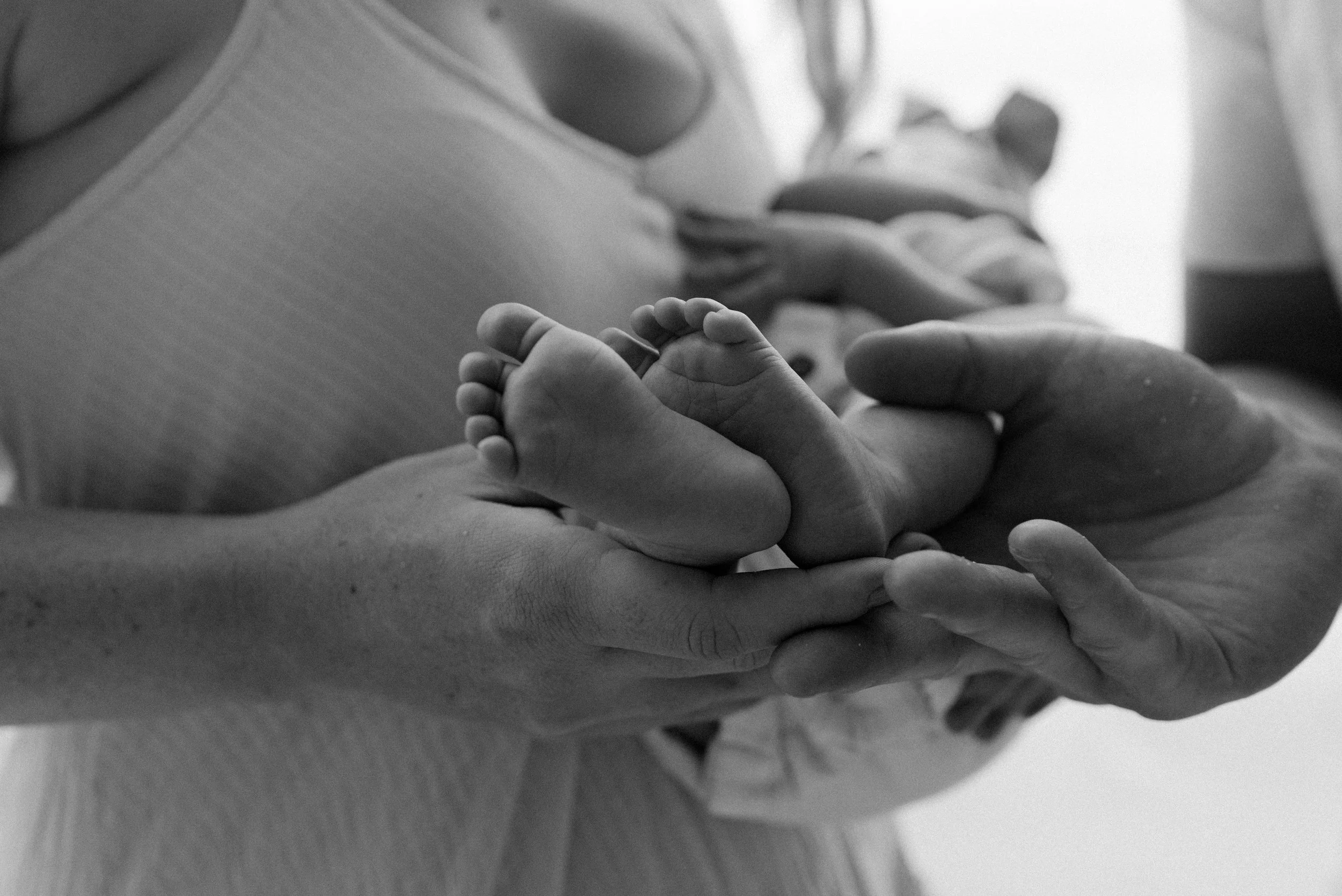 Close-up of an adult holding a baby's hand, focusing on their fingers. The baby's hand is small and chubby, and the adult's hand gently supports it.