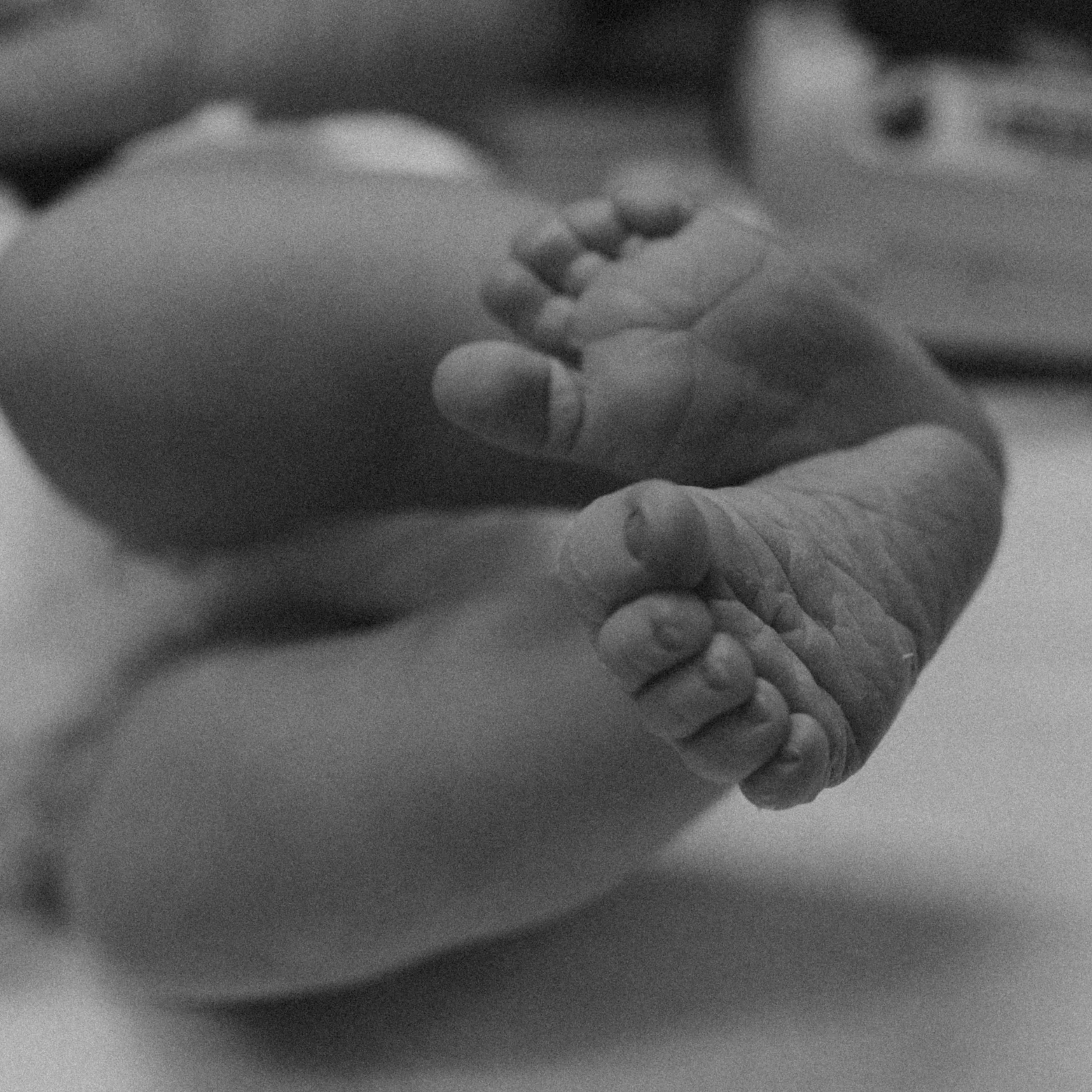 Close-up black and white photo of a person's face with eyes closed, resting on their hand.