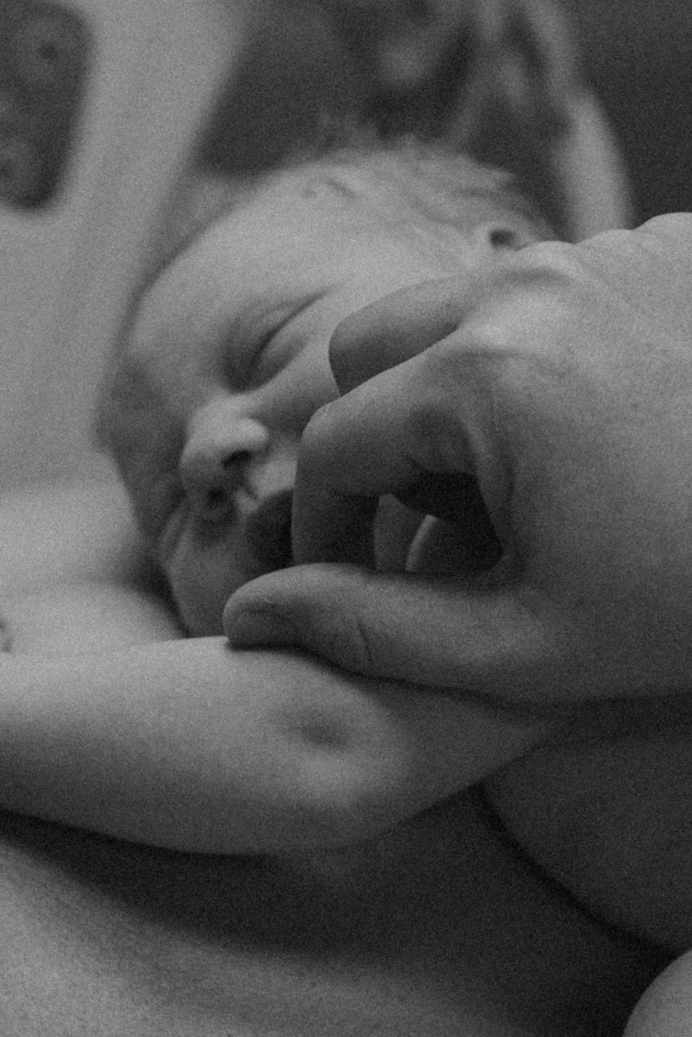 A close-up black and white photo of a person with closed eyes, gently touching their face with their hand, conveying a sense of calm and introspection.