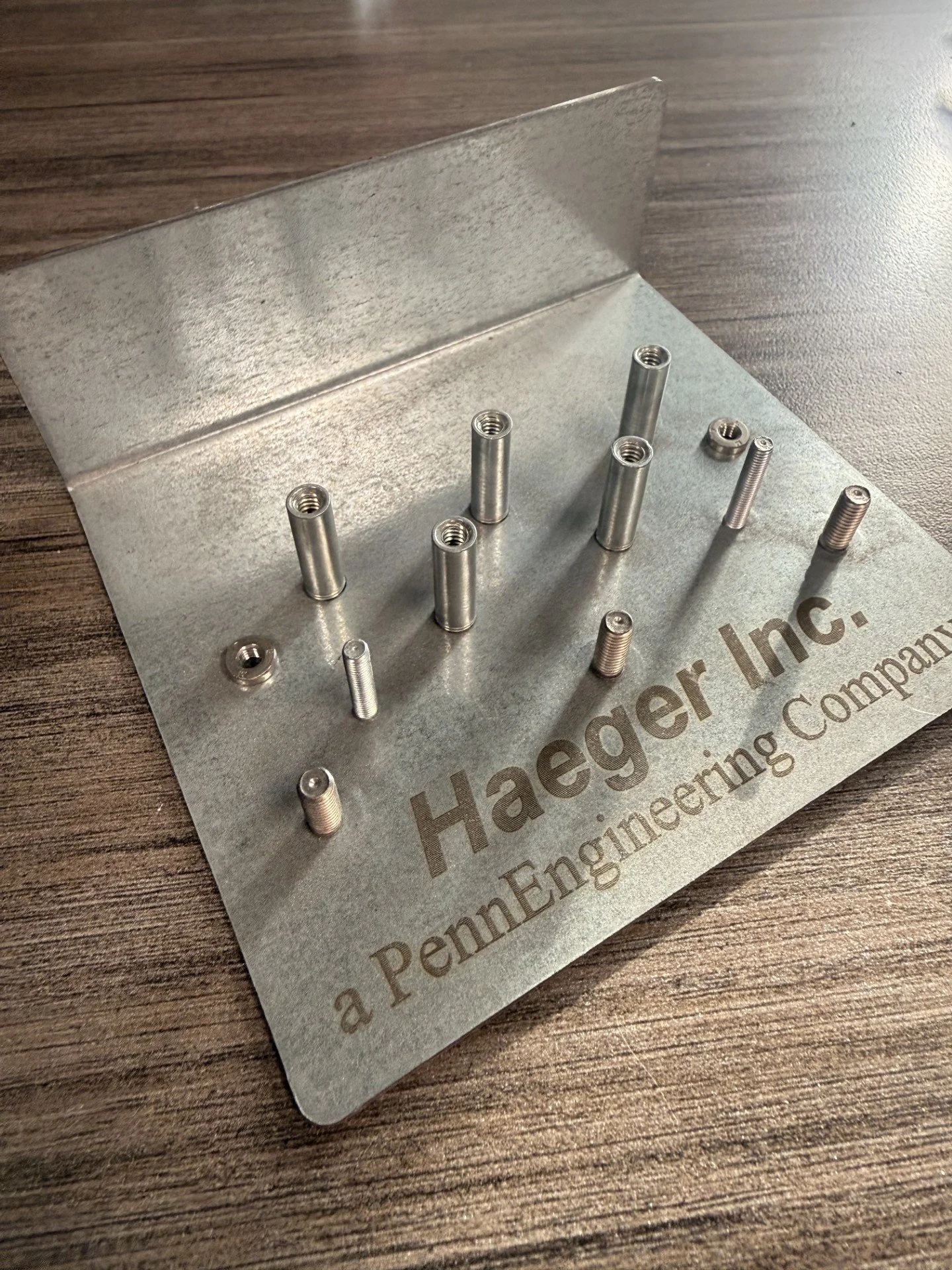 Sample of PennEngineering PEM nuts and PEM studs inserted into a test piece of sheet metal.