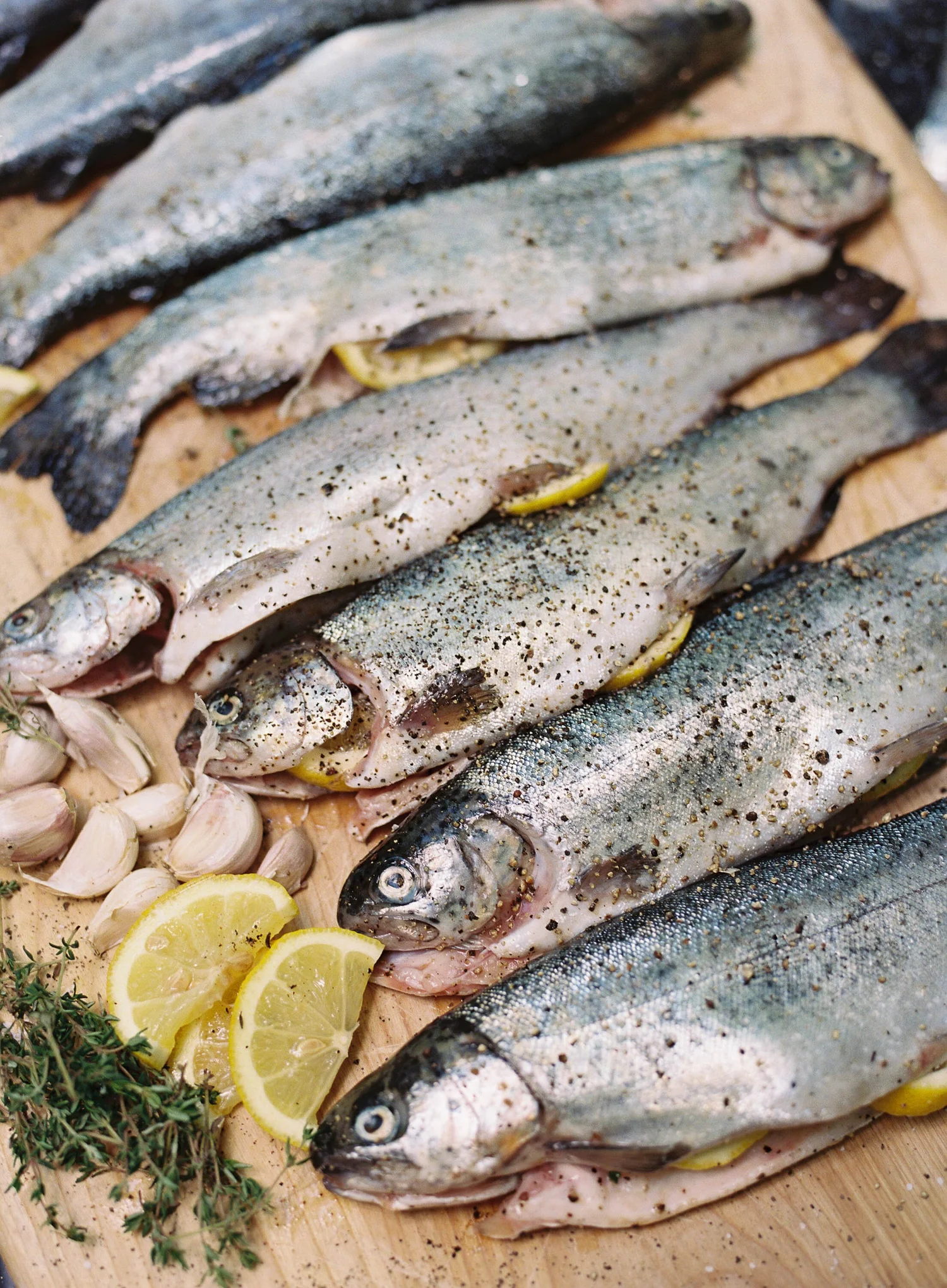 Fresh-caught trout on a wooden board with lemon and herbs