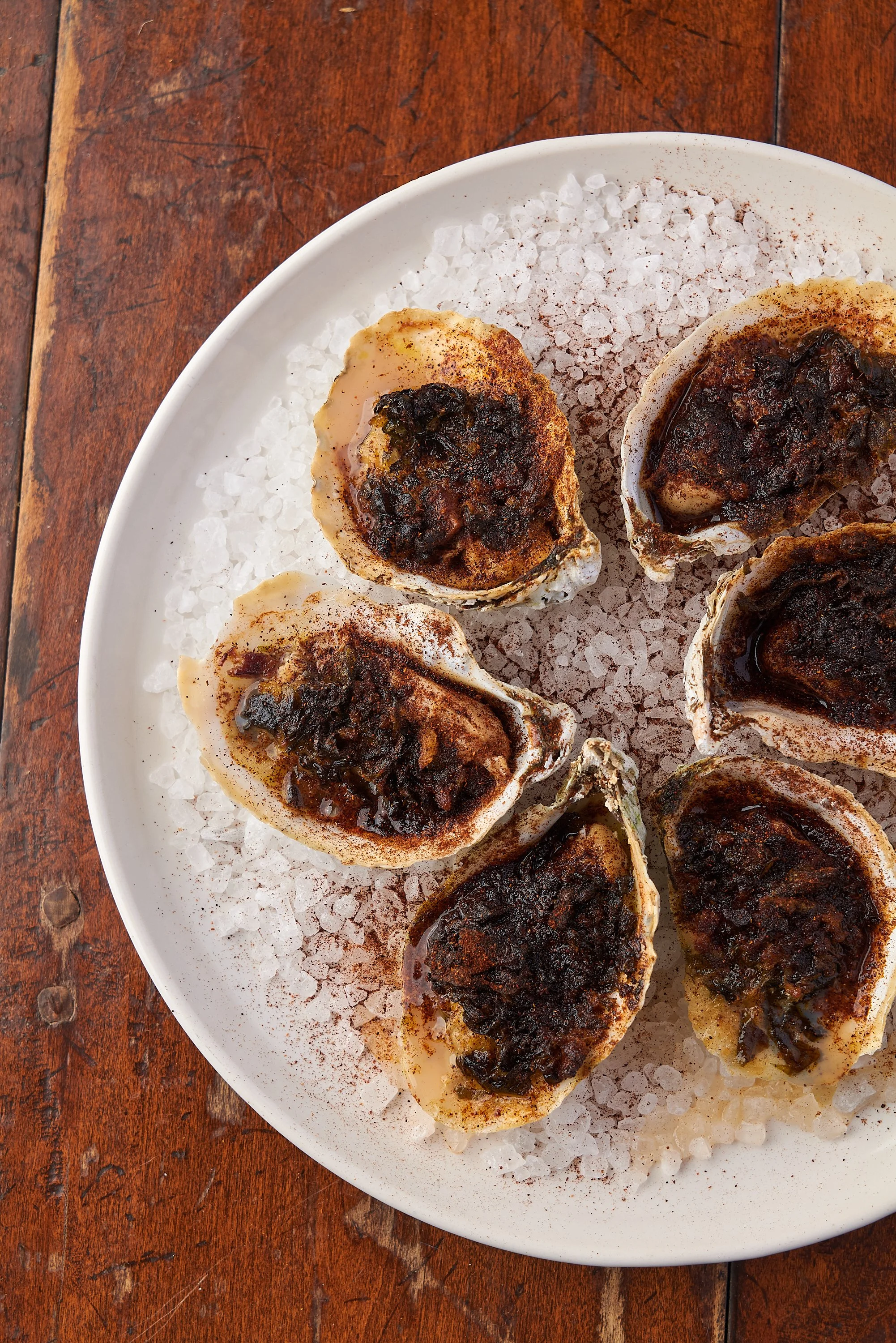 Roasted oysters with herb crust arranged on a ceramic plate, fine dining food photography by Cody Myers