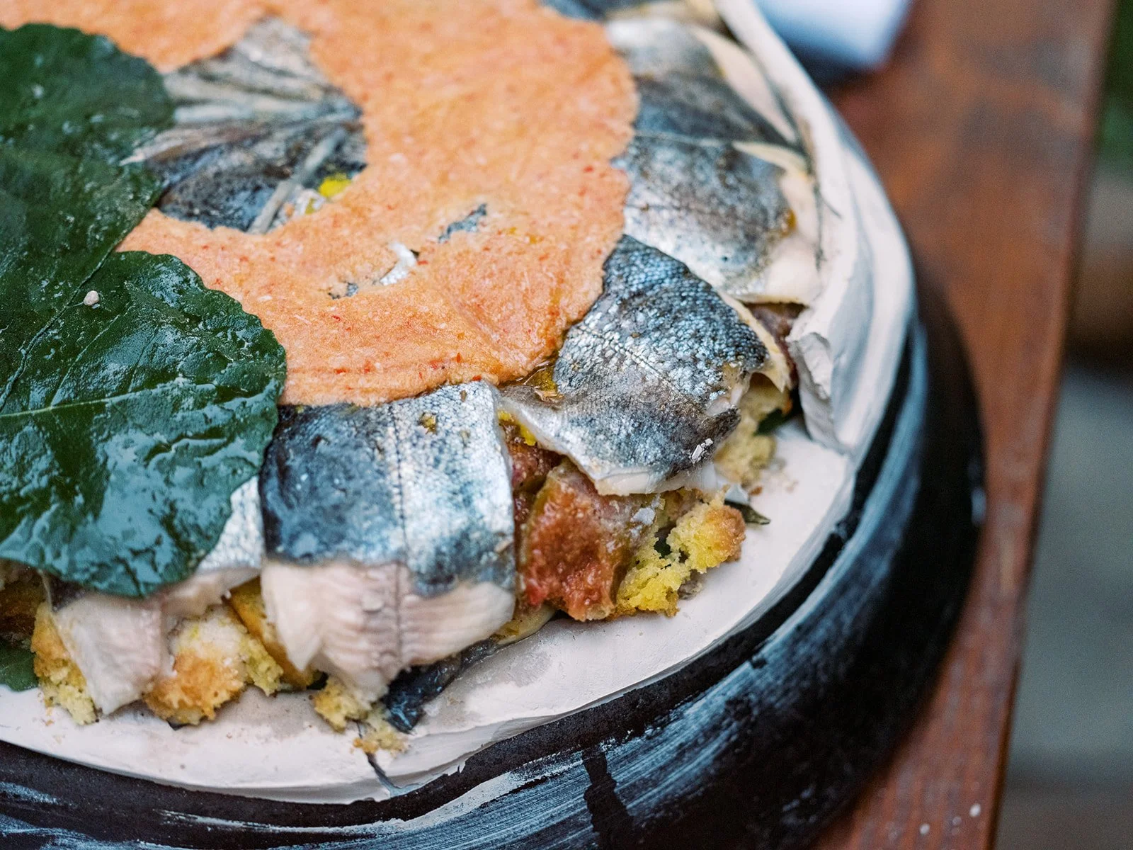 Whole fish cooked in a clay pot with herbs and crispy leaves, rustic food photography by Cody Myers