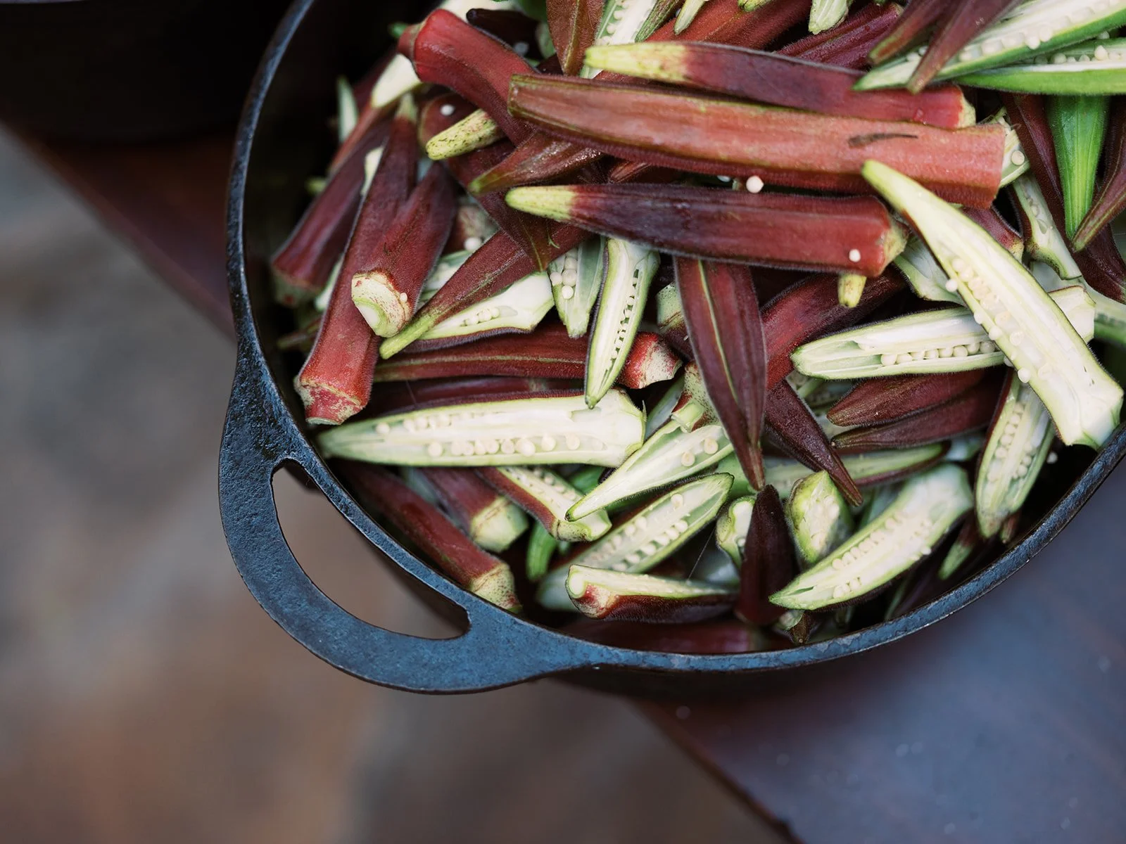 Fresh-cut okra in a cast iron skillet, farm-to-table food photography by Cody Myers