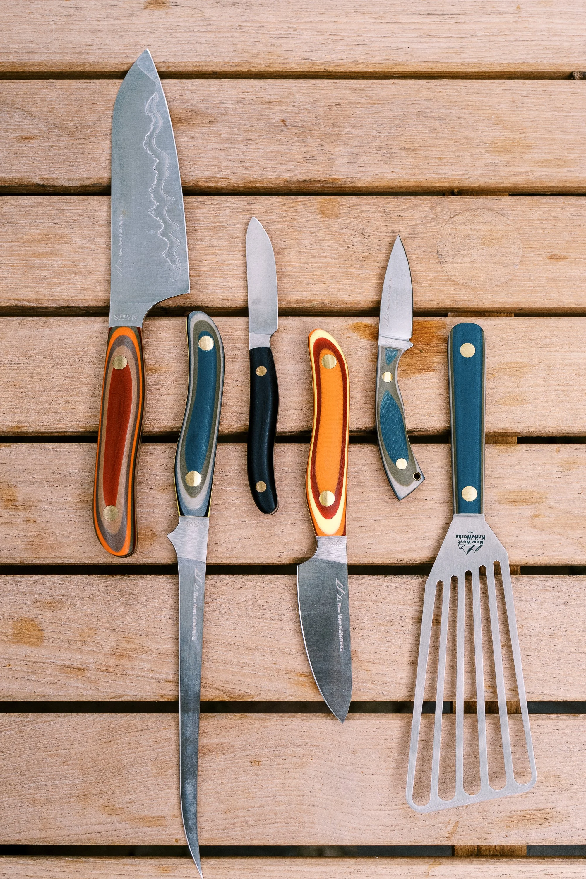 Chef's knives and grill tools laid out on a wooden surface, food and lifestyle photography by Cody Myers
