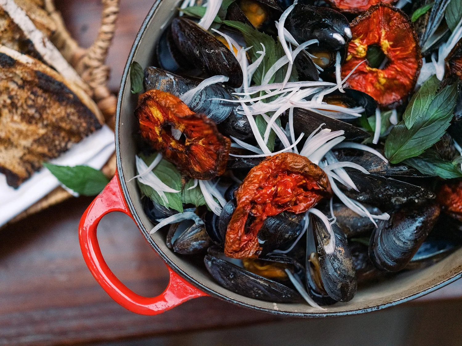 Mussels with roasted tomatoes in a red cast iron pot