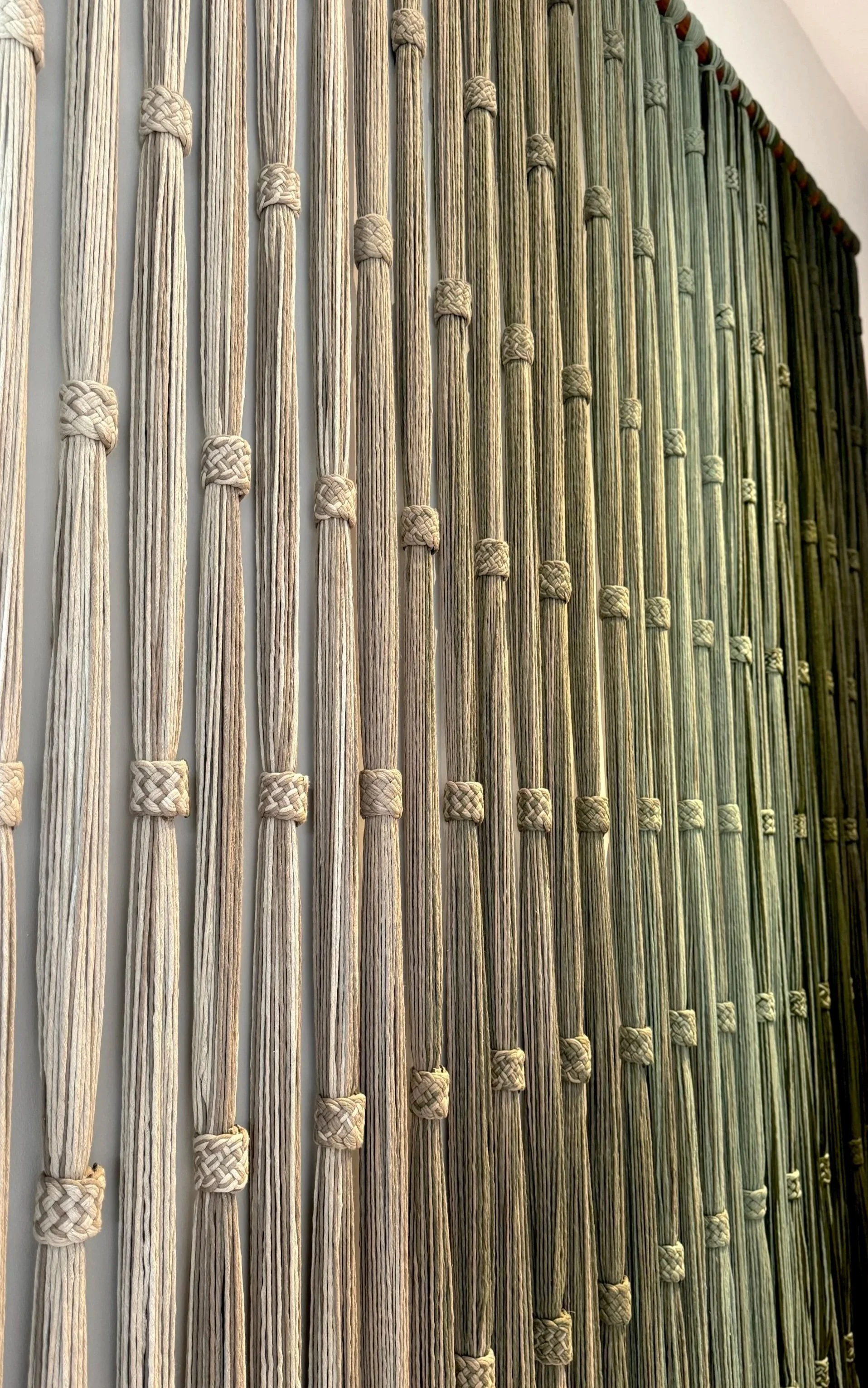 Muro decorativo hecho con cuerdas blancas amarradas en nudos, formando un patrón vertical