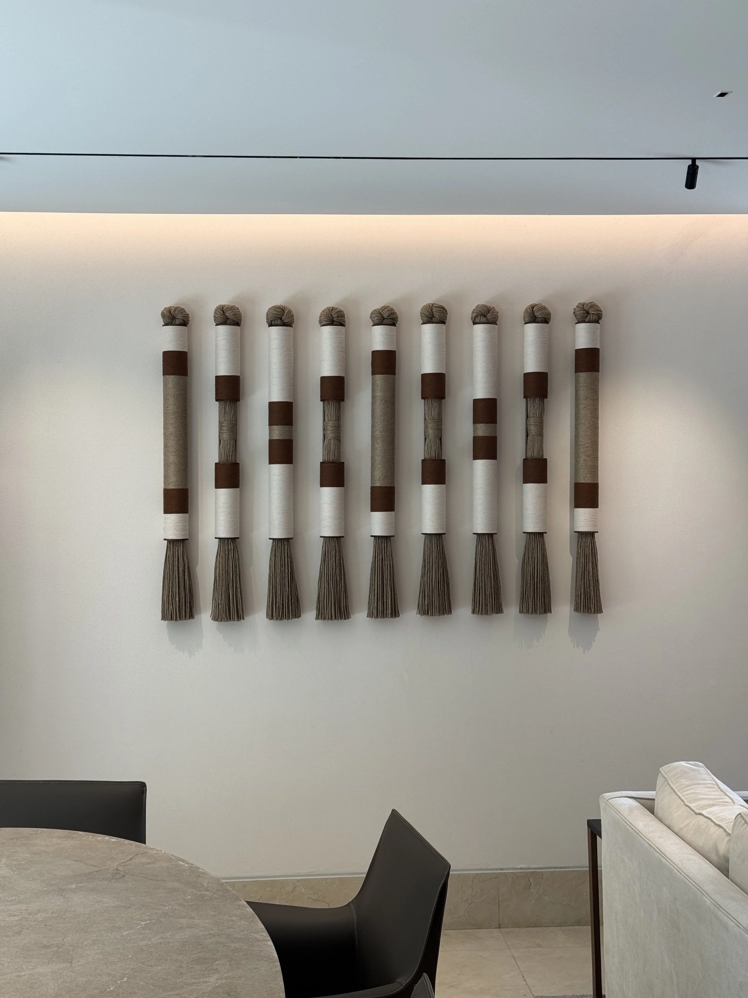 Decoración de pared con varillas de diferentes tamaños y colores en tonos neutros, en una sala moderna y minimalista.