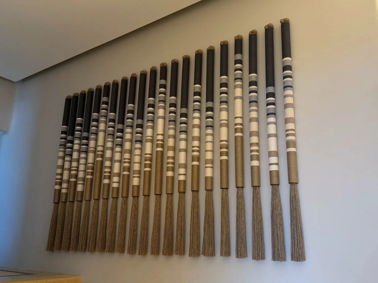 Decoración en la pared con varas largas de diferentes tonos colocadas verticalmente.