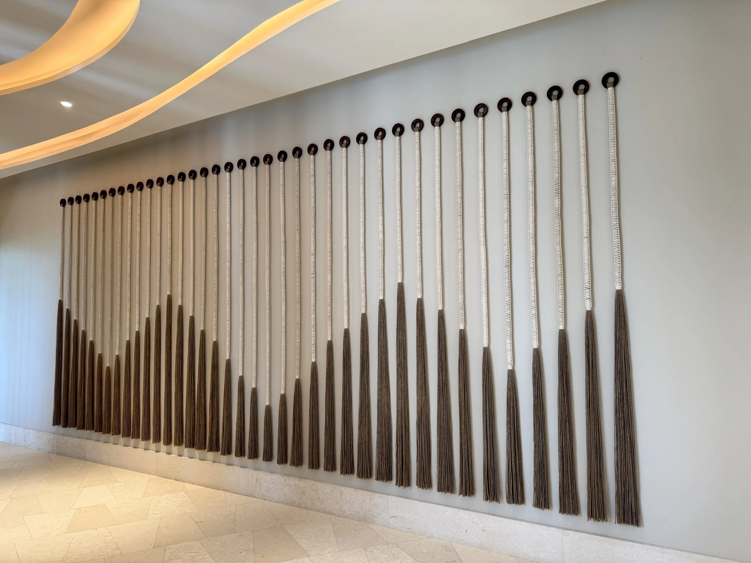 Un conjunto de hilos tejidos en pared en un espacio interior moderno con iluminación incorporada en el techo.