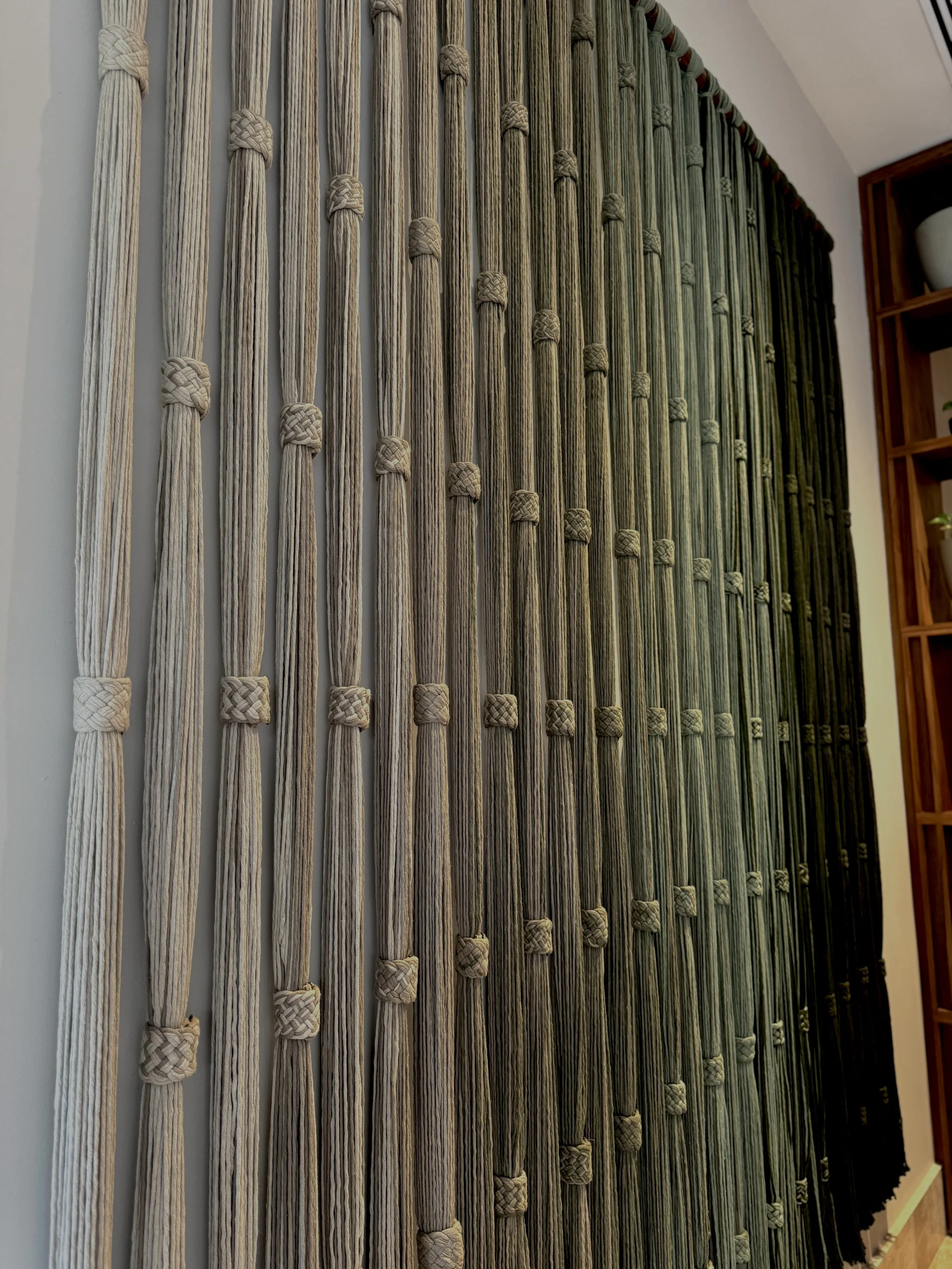 Pared decorativa con cuerdas y trenzas en un ambiente interior.