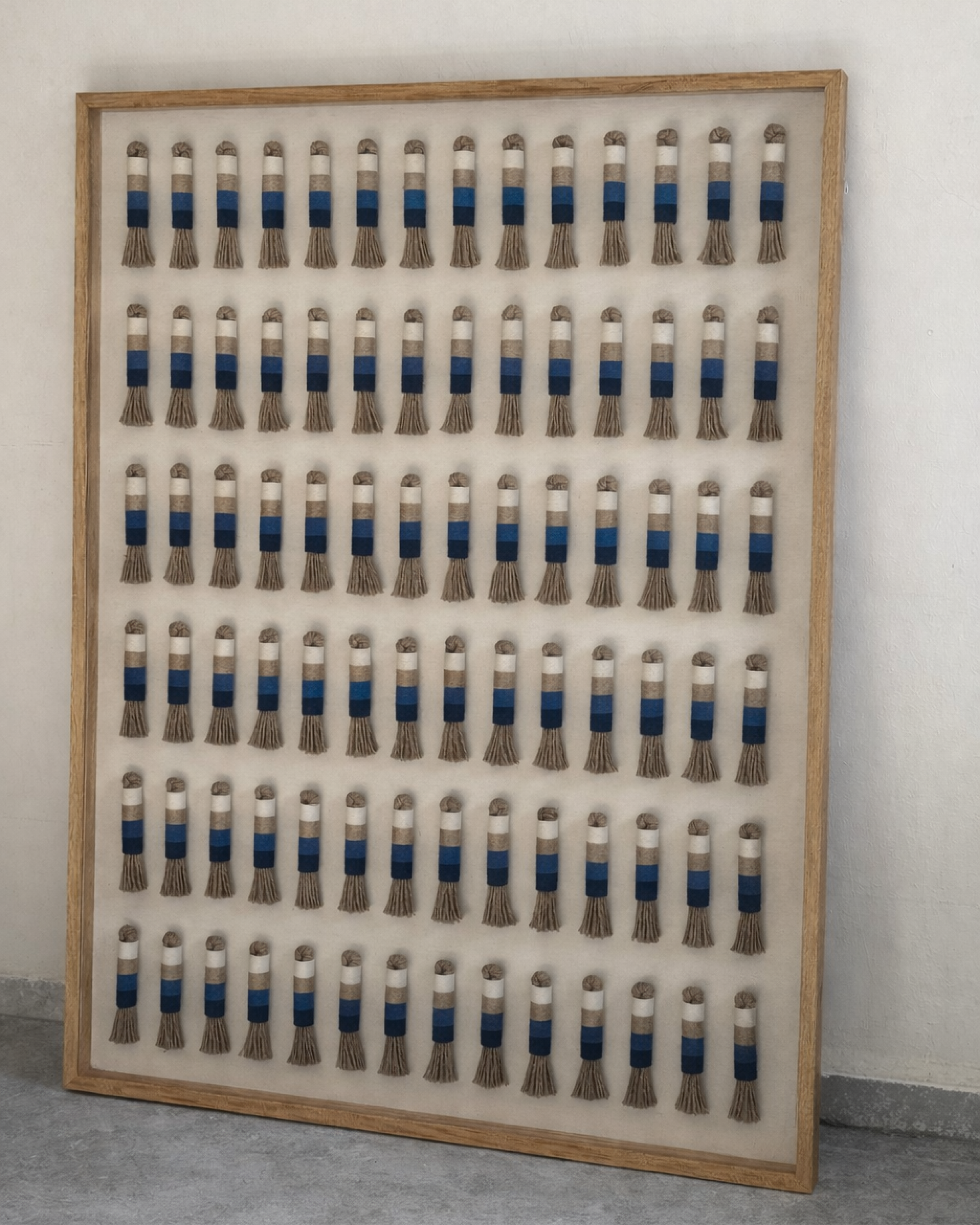 Conjunto de tubos tejidos de diferentes colores y grosores, organizados en un marco de madera
