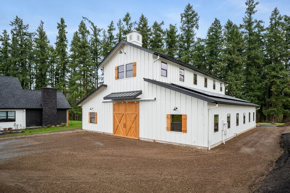 Opposite end of the barn showing cedar doors, shutters, and the long side elevation.