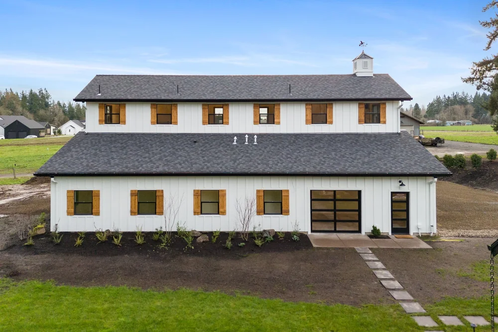 Side elevation with two rows of windows, cedar shutters, and a glass garage door.