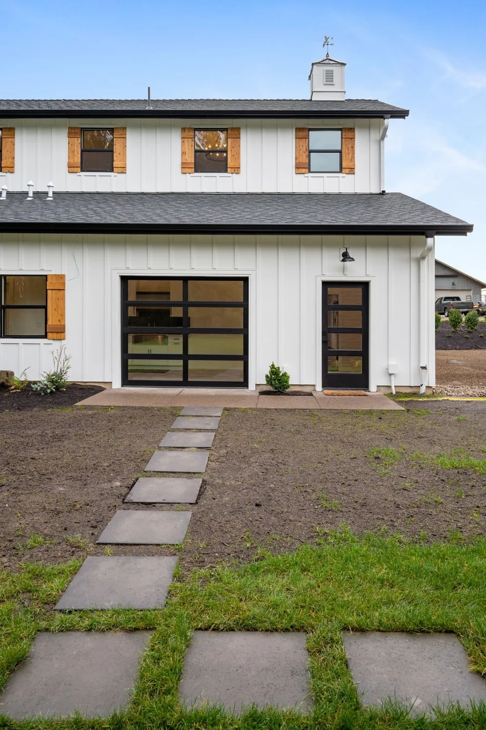 Stepping-stone path leading to the side entrance of the white barndominium.