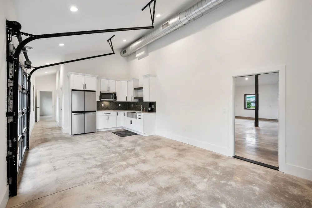 Kitchen opening into a flexible main-floor space beside a glass garage door.