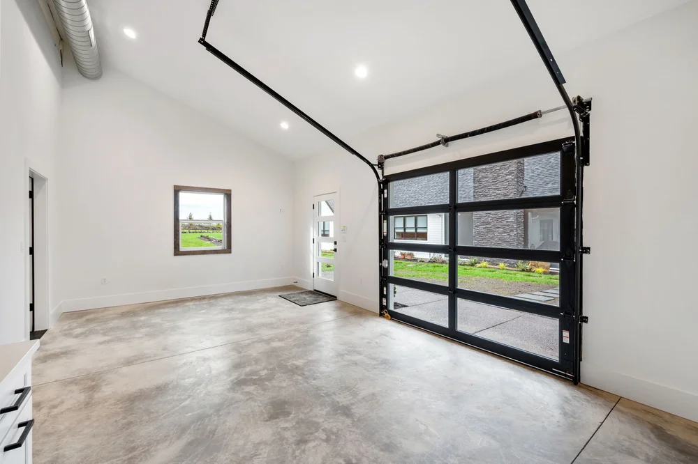 Open room with polished concrete flooring and a glass garage door.