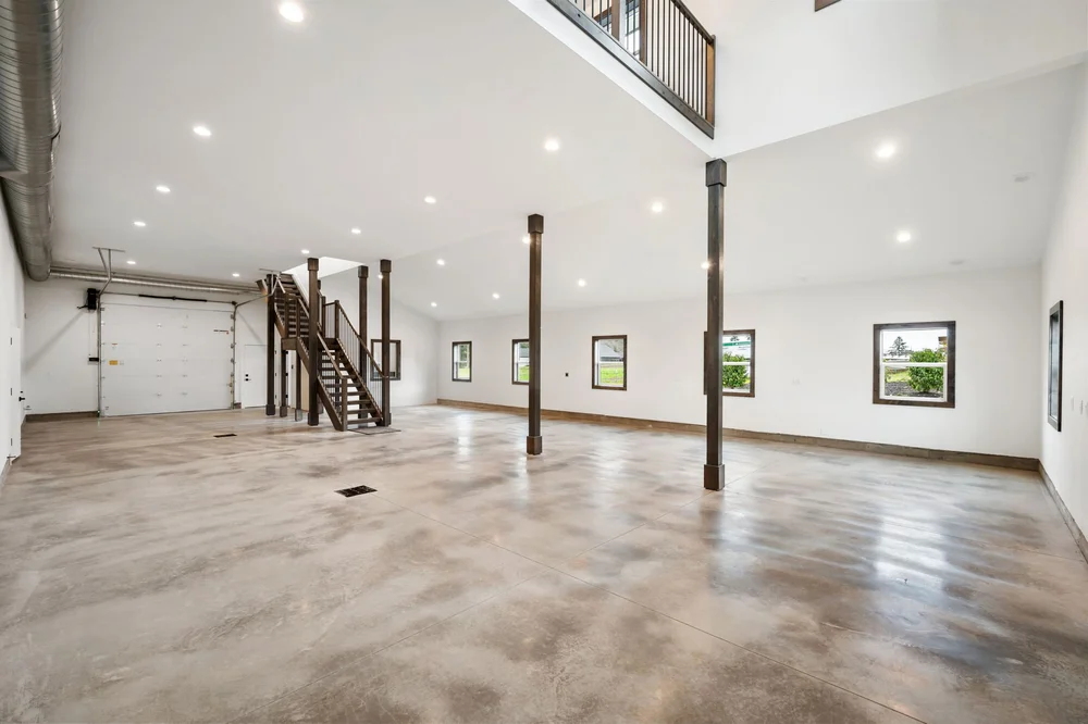 Expansive main-floor area with a tall ceiling and wood staircase leading to the loft.