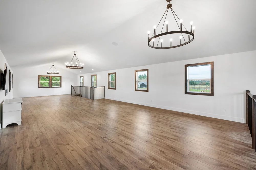 Spacious upstairs loft with wood flooring and circular chandeliers.