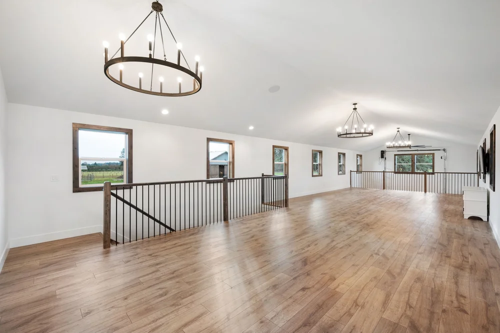 Long view through the upstairs loft with wood floors and multiple chandeliers.