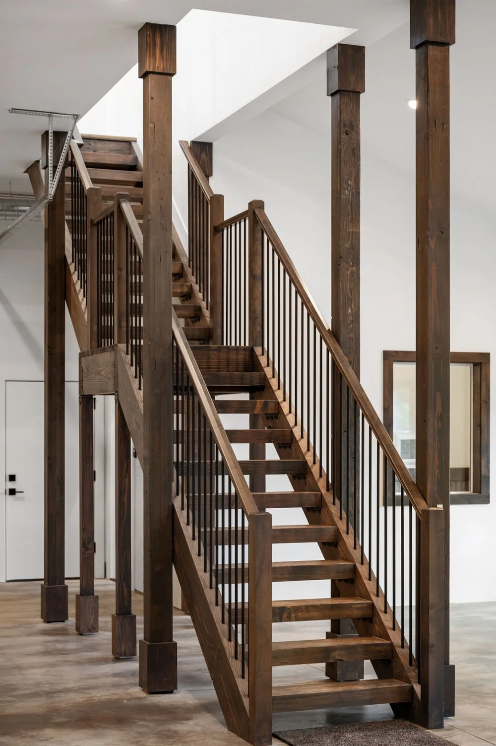 Wood staircase with dark balusters rising from the concrete main floor.