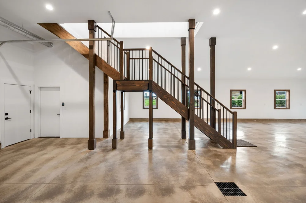 Wood staircase and posts in the open main-floor area of the barndominium.
