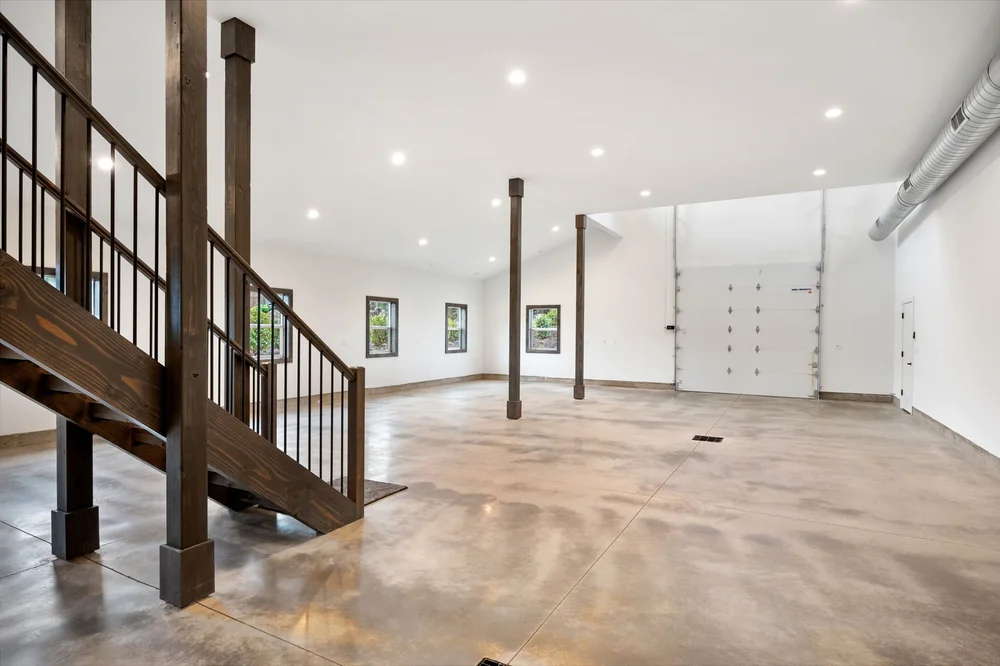 Open main floor with wood posts, stairs, and evenly spaced windows.
