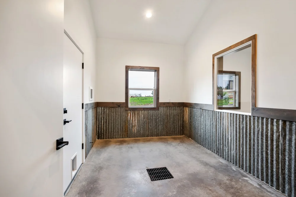 Indoor chicken coop with corrugated metal wall panels, windows, and a floor drain.