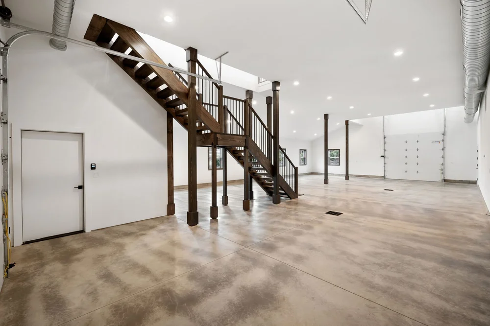 Broad view of the main floor, wood staircase, and insulated garage door.