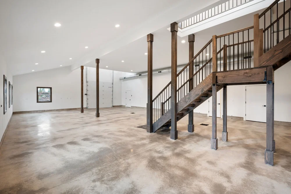 Main-floor open area with windows and the wood staircase along one side.