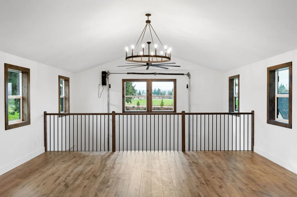 Loft landing with dark balusters and a large window at the end of the space.