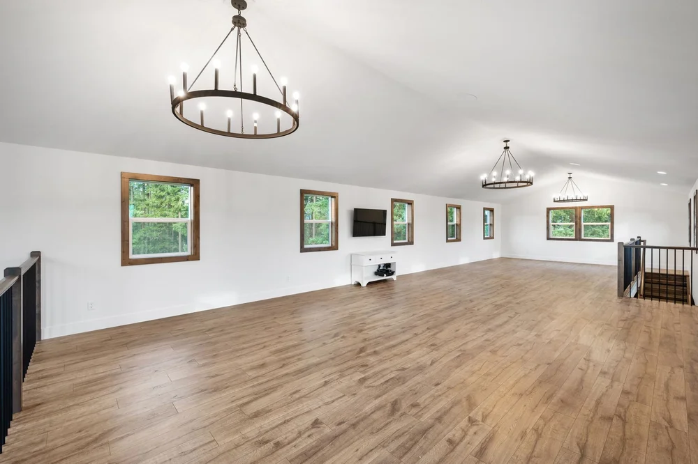 Wide loft interior with wood floors, white walls, and circular chandeliers.