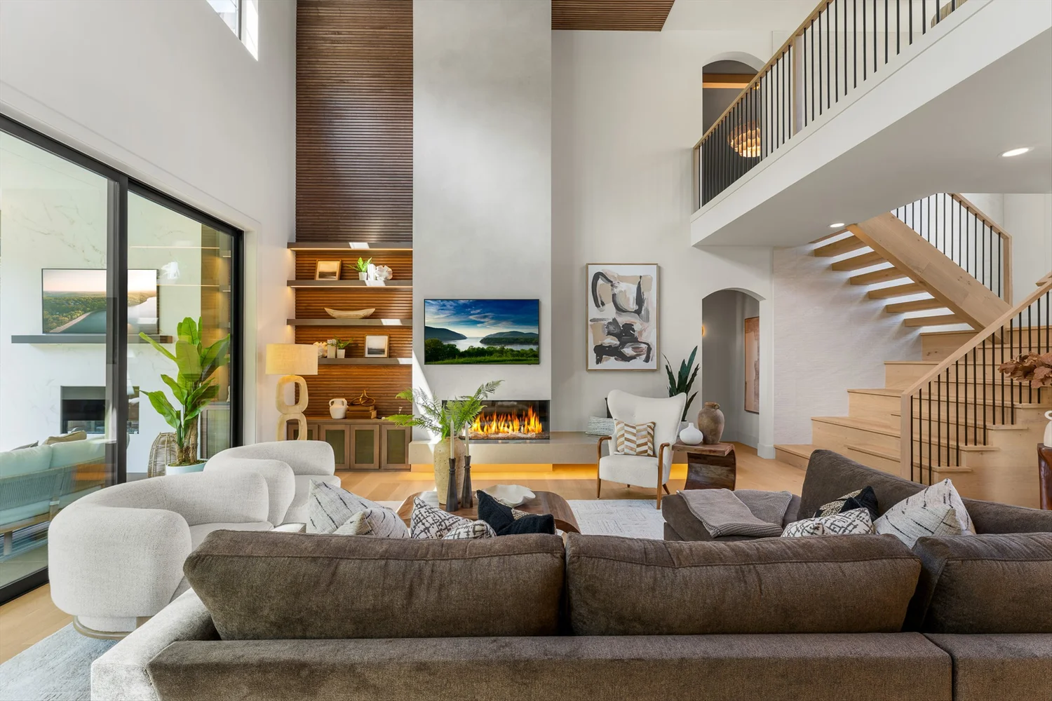 A Designer Built Homes living room with a tall fireplace, warm wood details, and an open staircase