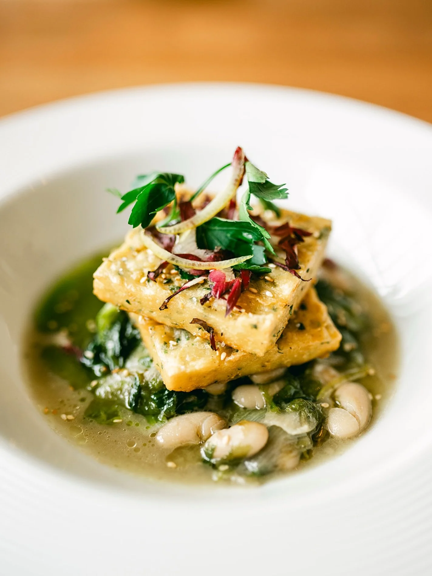 Crispy Chickpea Panelle served with escarole, cannellini beans, sesame, and a touch of lemon 🍋

A light, flavorful, and vegan favorite. ✨

#lucastonybrook