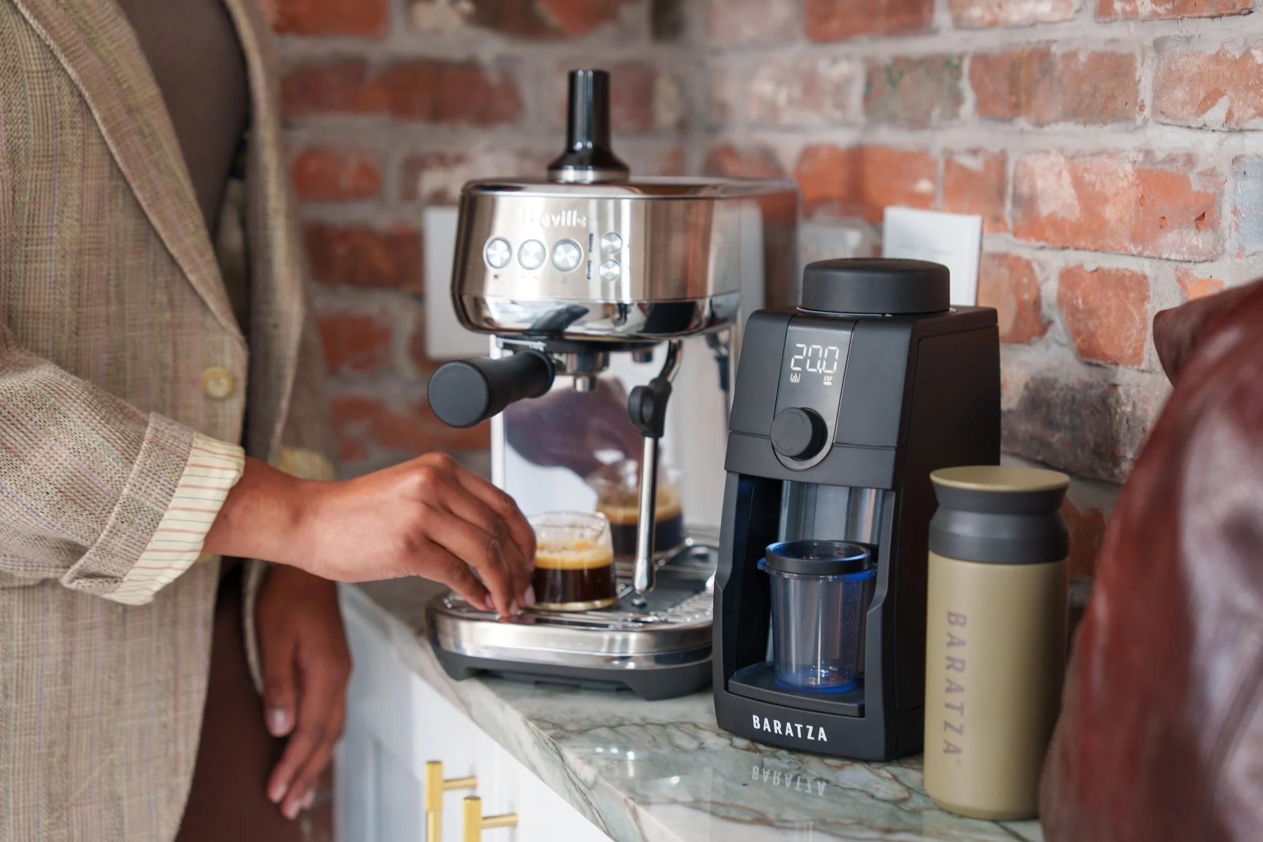 image of black baratza encore esp pro next to person taking espresso cup out from underneath espresso machine