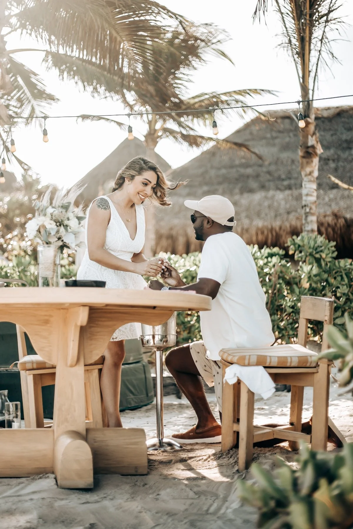 Man proposing to woman at beachside table, tropical setting at Tulum Beach.