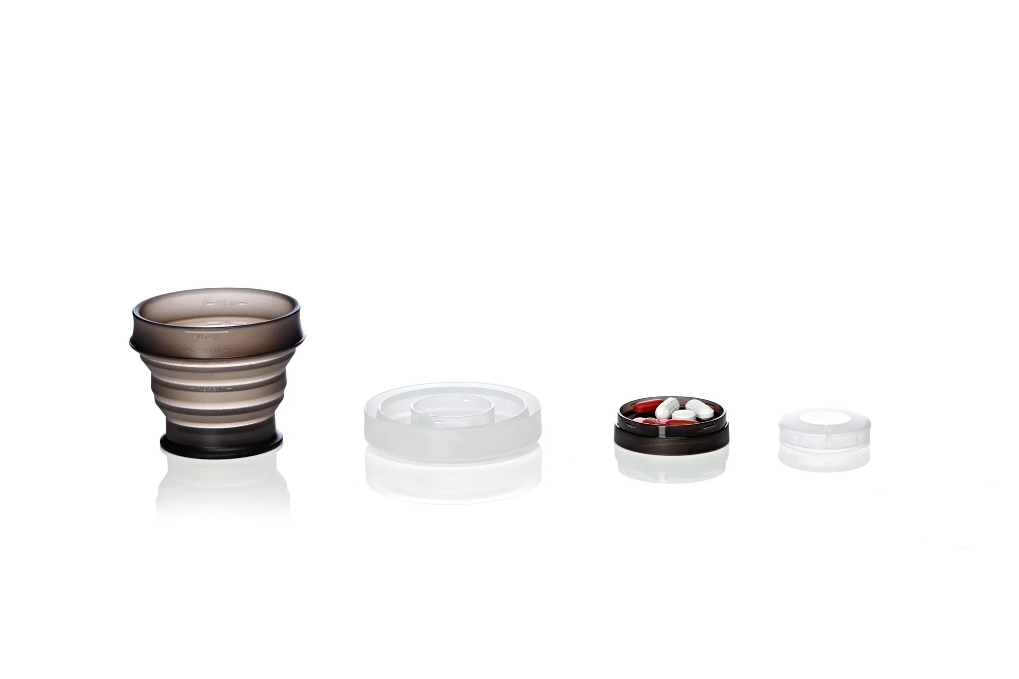 Collapsible travel cup with pill compartment and cover on white background.