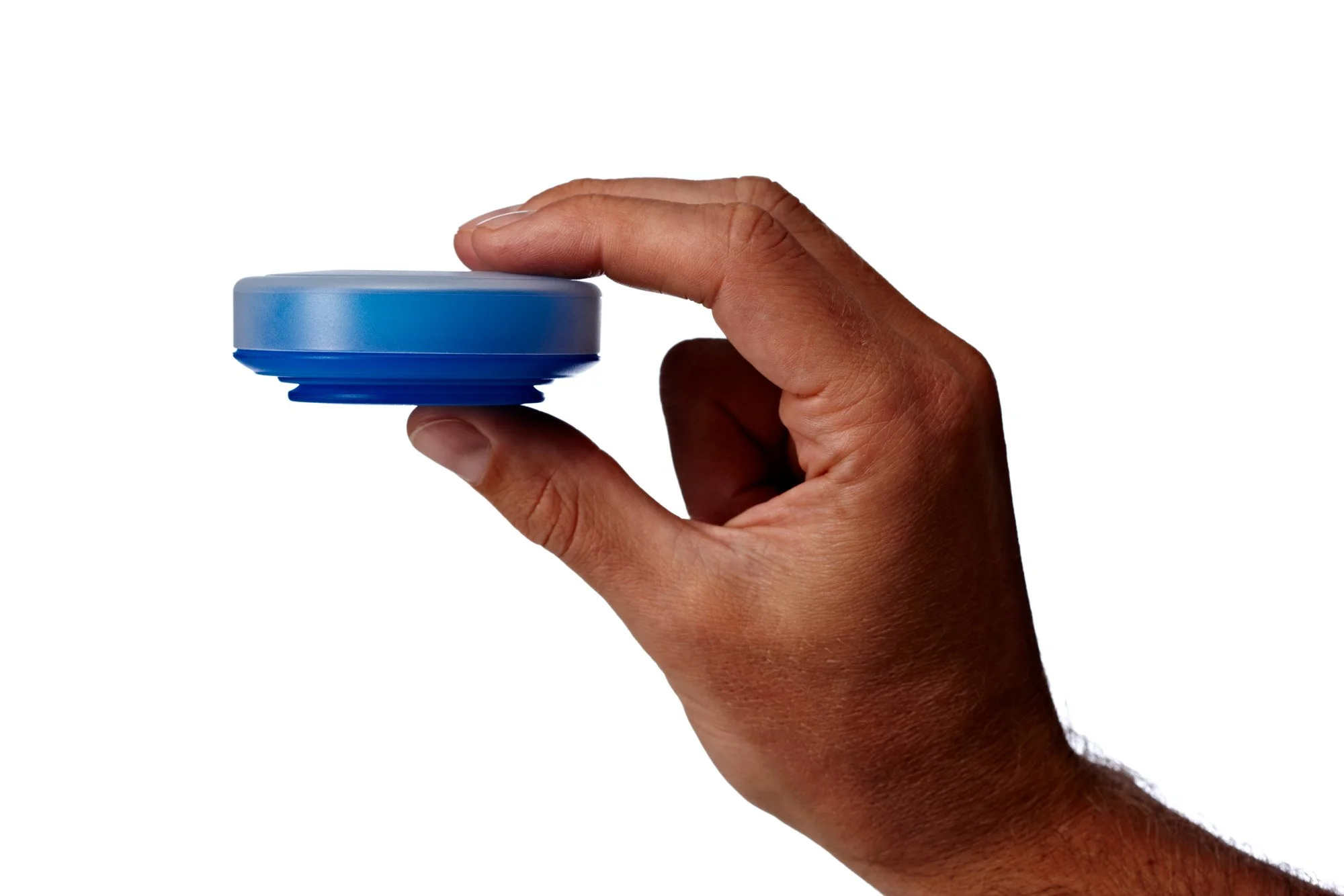Hand holding a round blue object with a white top on a white background.