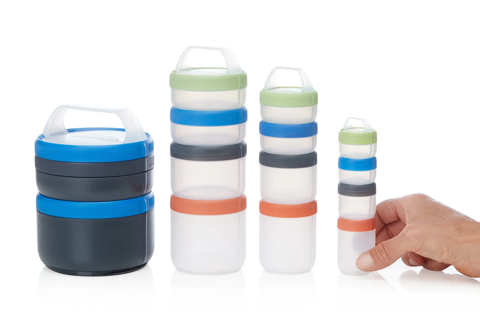 Stackable food containers with color-coded lids in various sizes, including blue, green, gray, and orange, arranged in a row with a hand touching the smallest one.