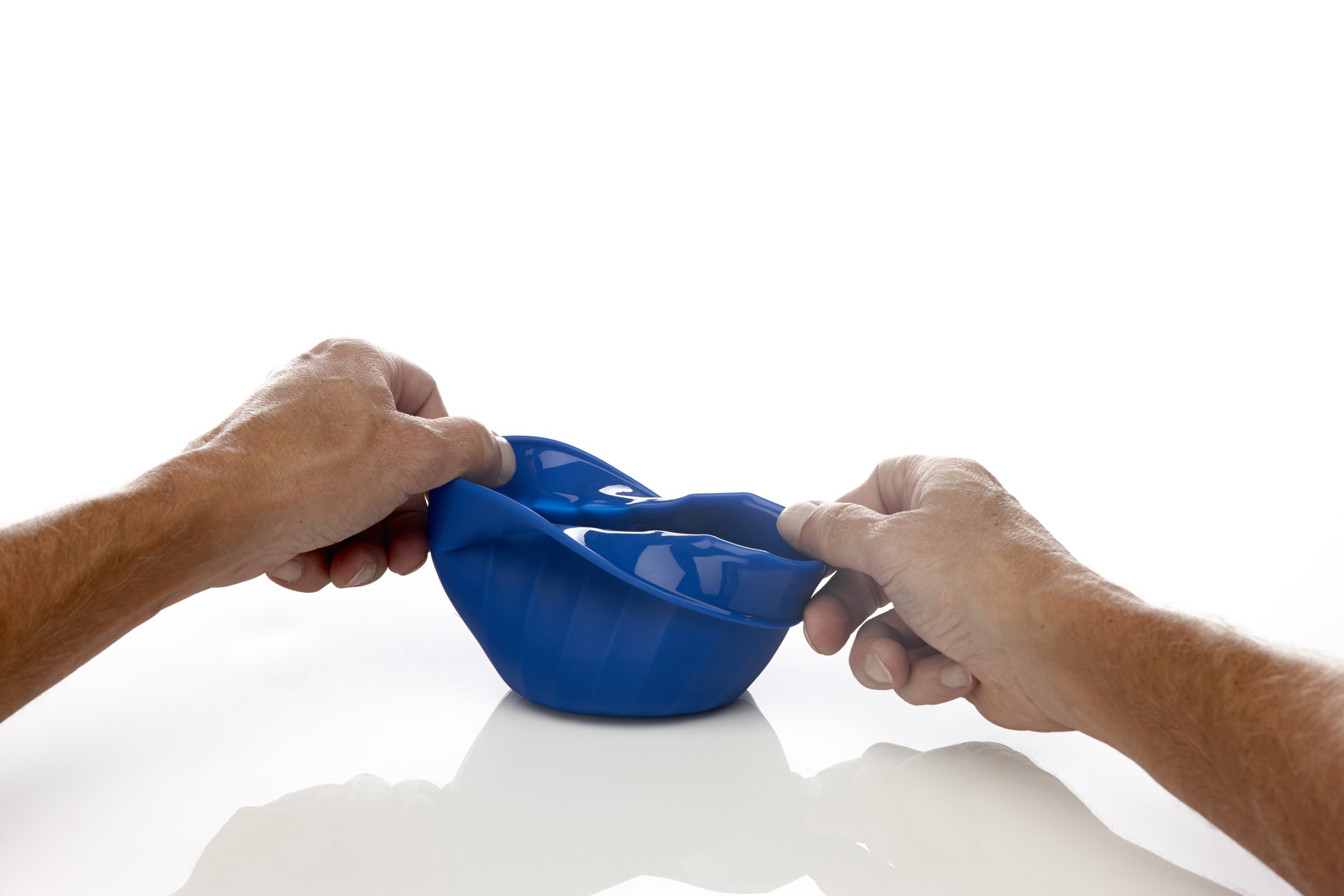 Two hands stretching a blue silicone bowl.