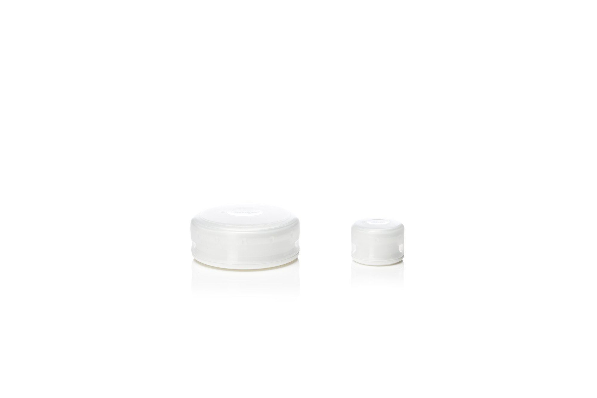 Two white plastic jar lids of different sizes on a white background.