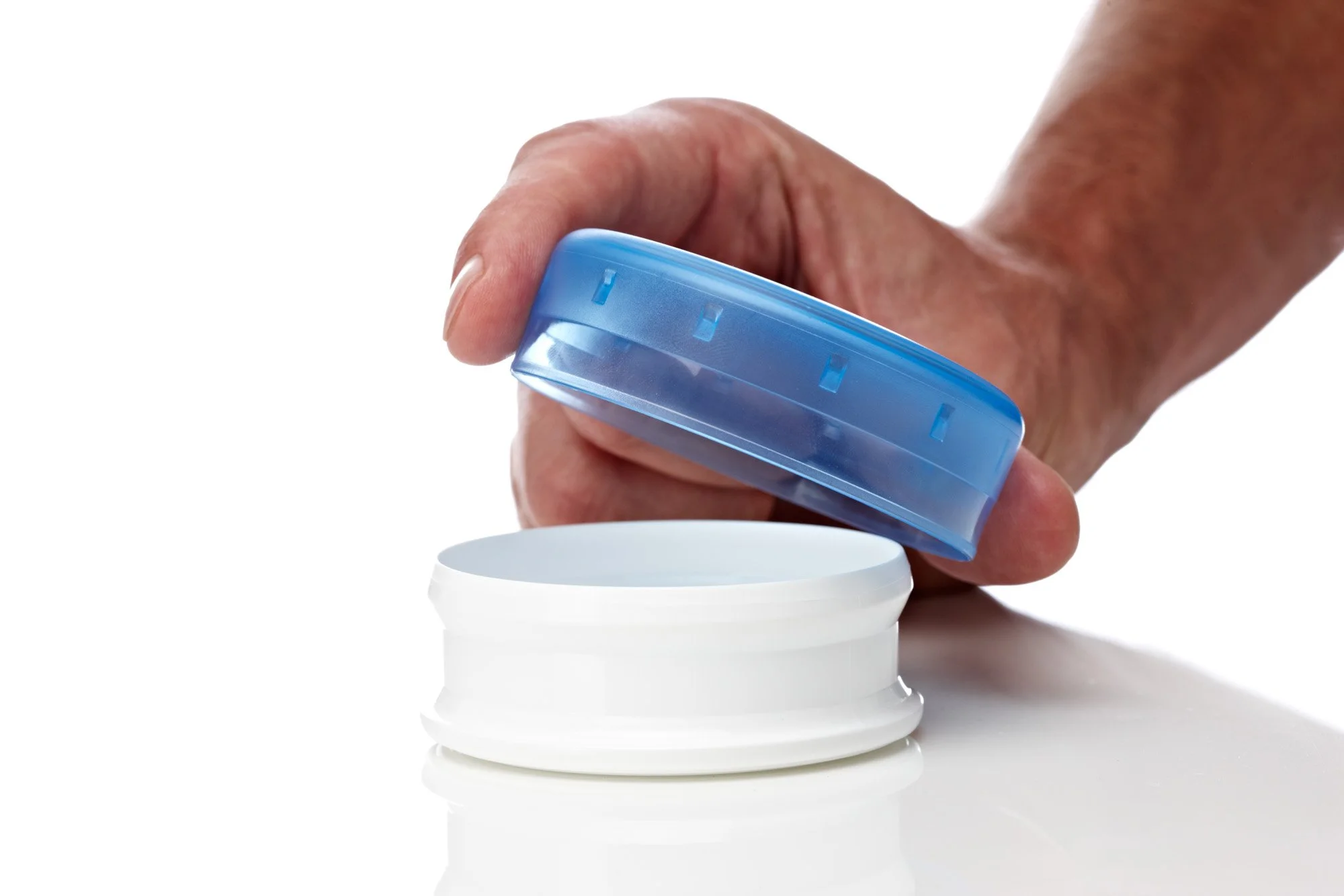 Hand opening a container with blue lid