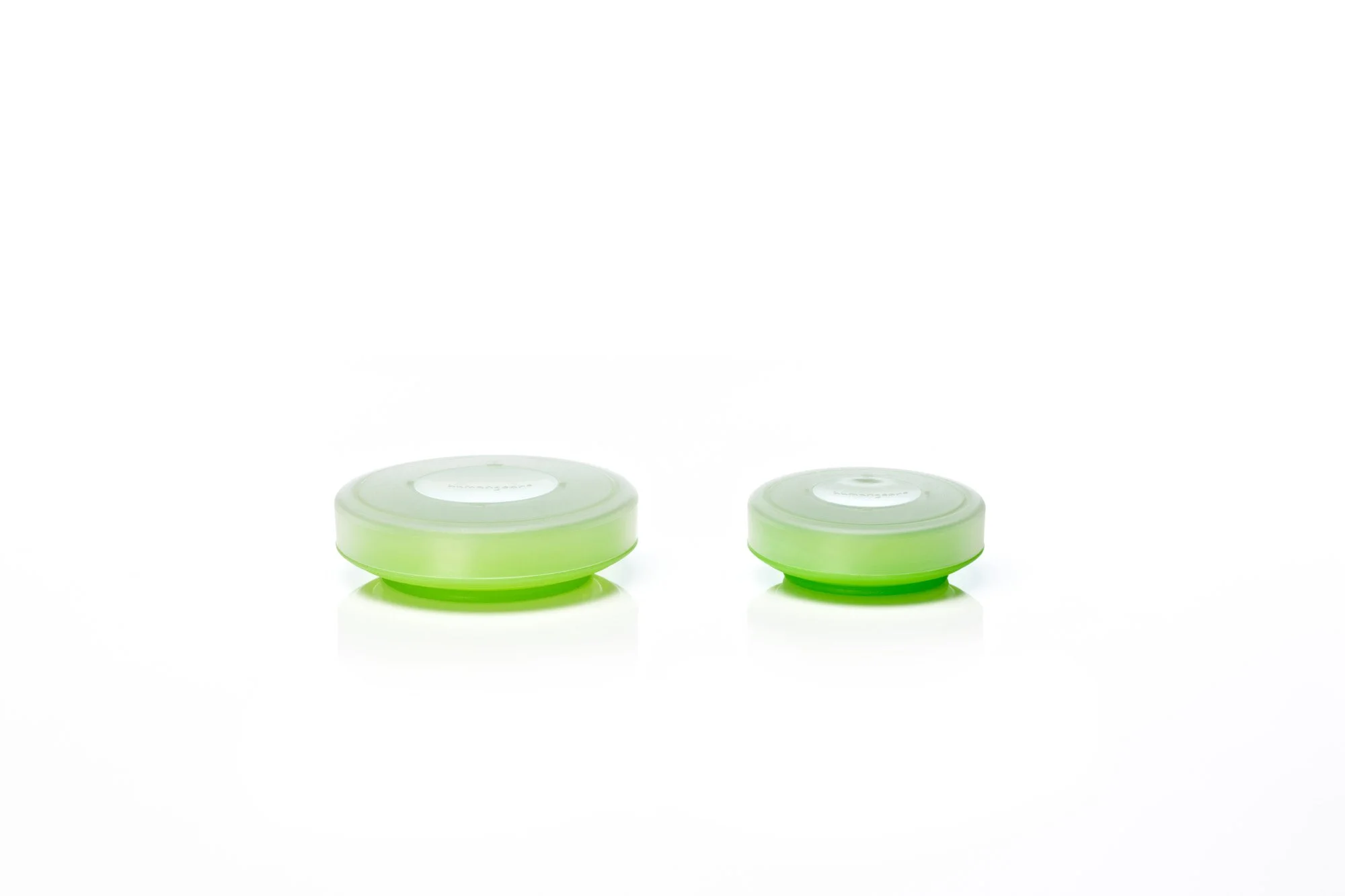 Two green silicone lids on a white background