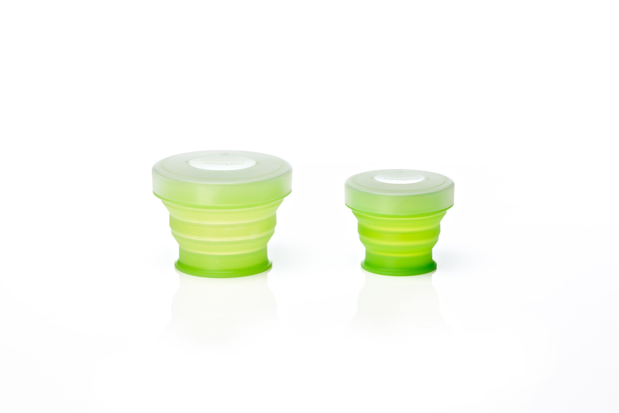 Two green collapsible silicone containers with transparent lids on a white background.