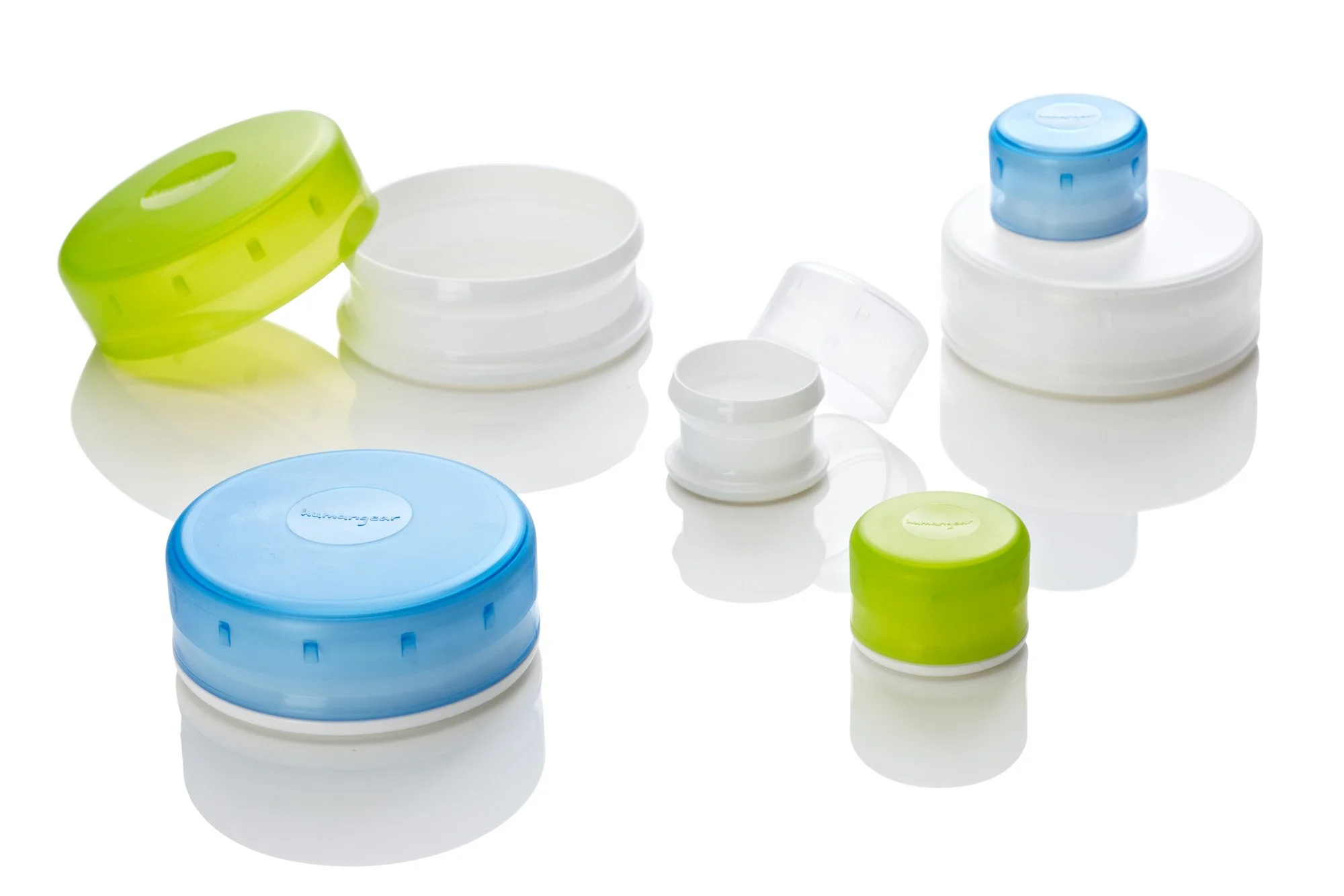 Assorted plastic caps and containers in green, blue, and white on a reflective surface.
