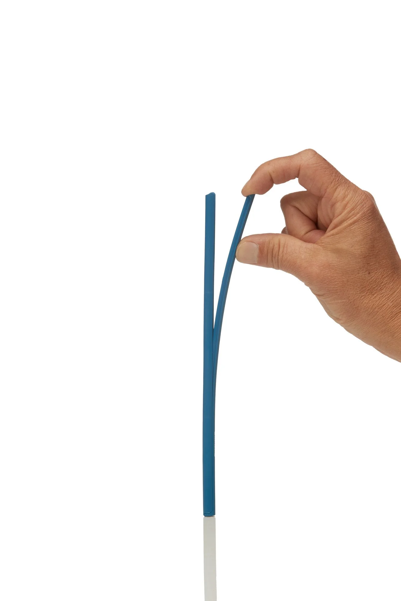 Hand bending a blue plastic strip on white background.